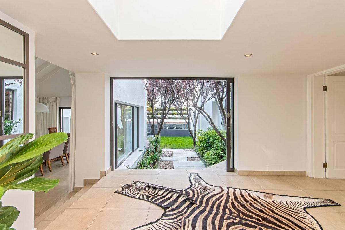 Bright living area featuring a large skylight, tiled flooring, and seamless access to the rear garden through expansive sliding glass doors.