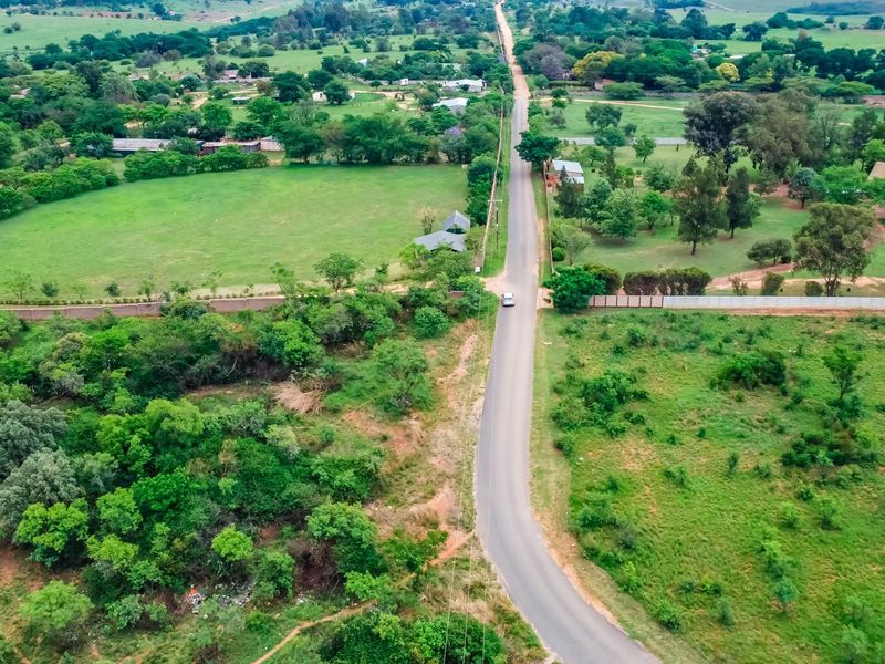 An aerial view of the commercial vacant land showing the surrounding landscape, access road, and natural vegetation.