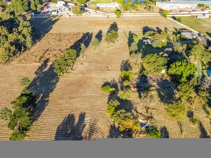 An aerial view of a large farm property featuring expansive open land, mature trees, and surrounding rural landscape.