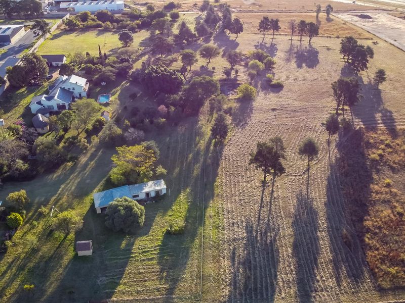 Aerial view of the farm property showing the main dwelling, outbuildings, expansive grounds, and surrounding landscape.