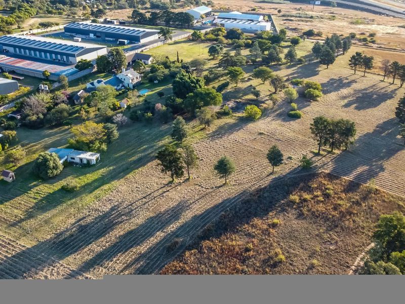 Aerial view of a large farm property featuring expansive open land, mature trees, and various outbuildings in a rural setting.