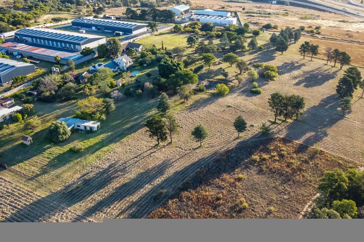 Aerial view of a large farm property featuring expansive open land, mature trees, and various outbuildings in a rural setting.
