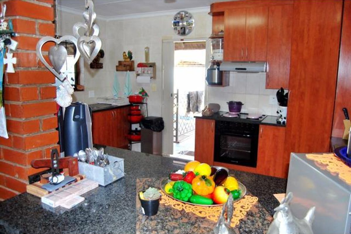 A functional kitchen featuring wood-finish cabinetry, a dark granite countertop, and a built-in oven with an extractor fan.