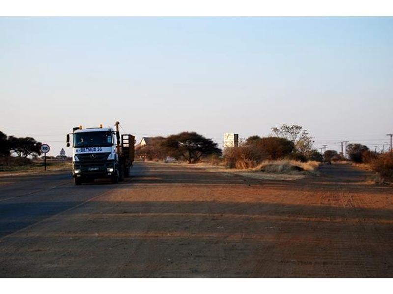 A view of the asphalt road and surrounding unpaved land area, showing access to the commercial property.
