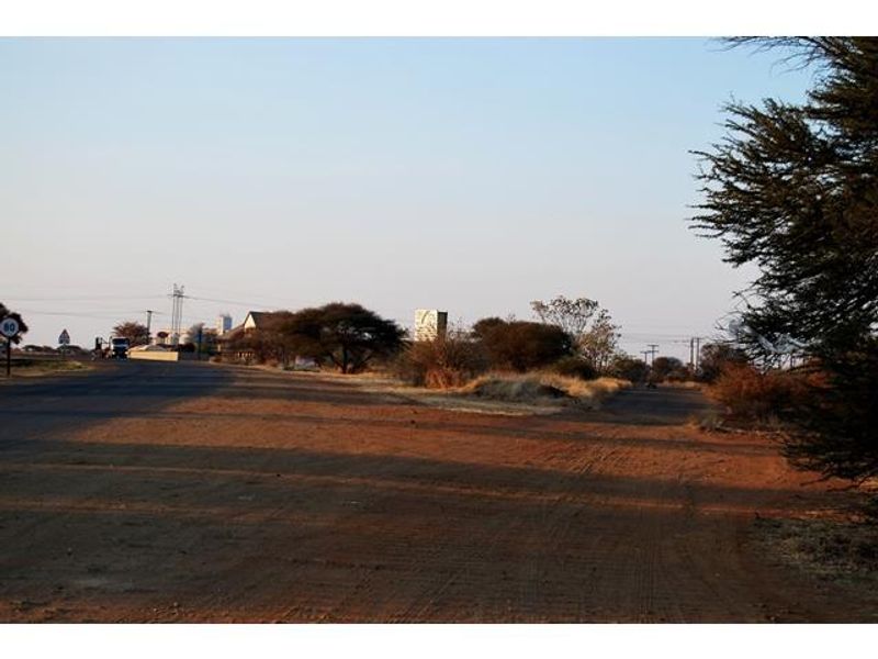 A view of the unpaved road access and surrounding landscape for the vacant commercial land.