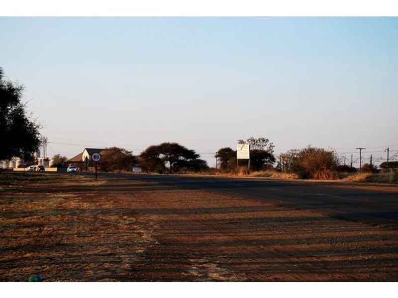 A view of the public road and surrounding landscape adjacent to the commercial vacant land property.