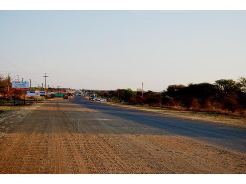 A view of the paved road and surrounding landscape adjacent to the commercial vacant land property.