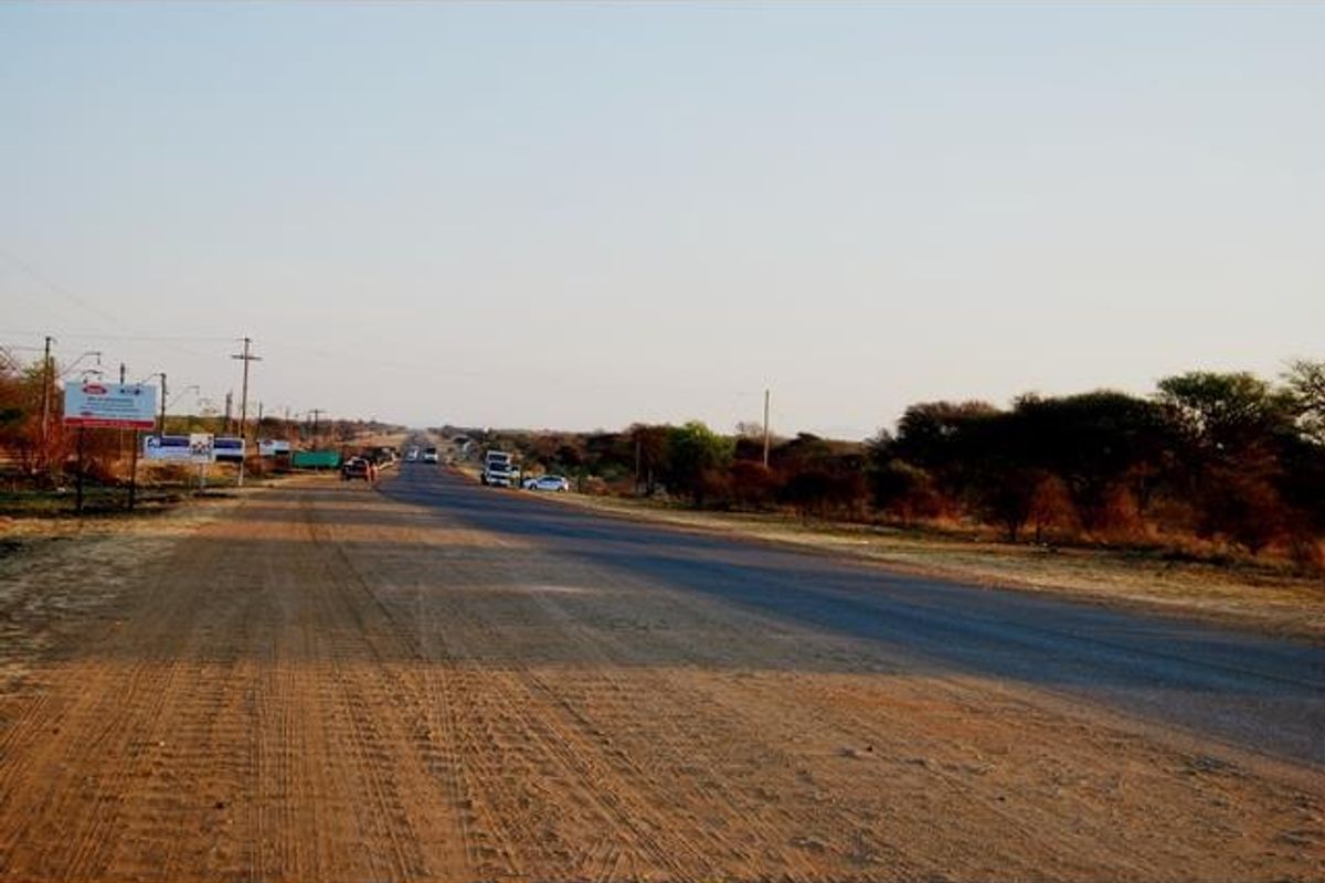 A view of the paved road and surrounding landscape adjacent to the commercial vacant land property.