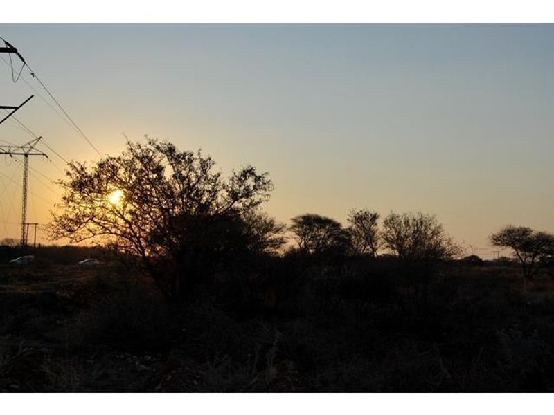 A scenic view of the vacant land at sunset, featuring natural vegetation and visible electricity infrastructure.