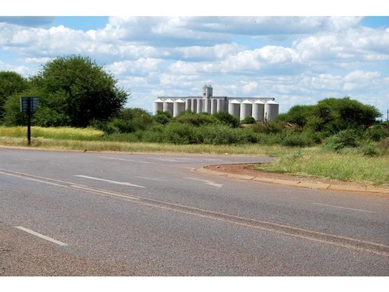 A view of the surrounding landscape featuring a large industrial silo complex in the distance, accessible via the adjacent paved road.