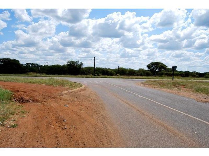 A view of the paved road intersection and surrounding natural landscape, providing access to the vacant residential land.