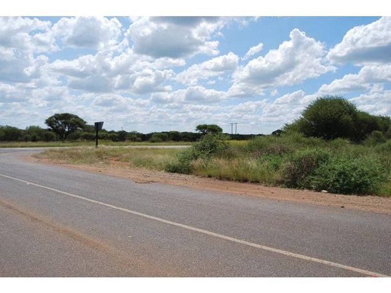 A view of the vacant residential land from the adjacent paved road, featuring natural vegetation and open terrain.