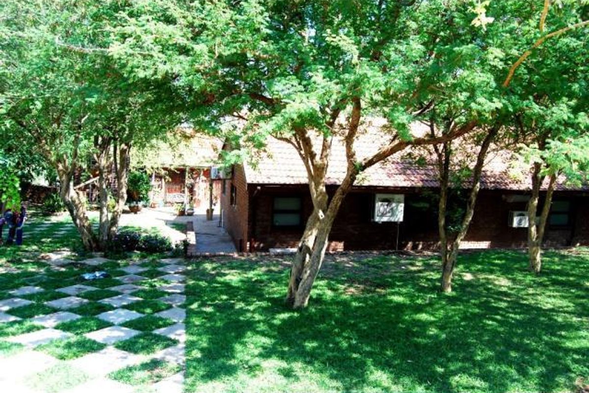Rear view of the farm property featuring a brick exterior, tiled roof, and established garden with a paved walkway.