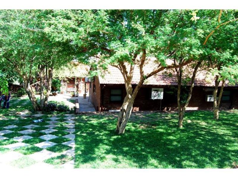 Rear view of the farm property featuring a brick exterior, tiled roof, and established garden with a paved walkway.