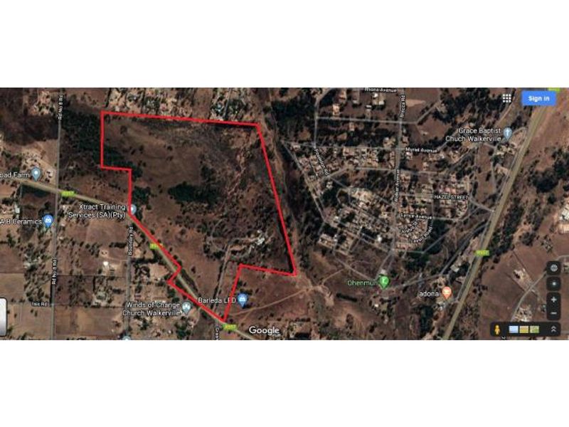 Aerial view of a large vacant residential land parcel with property boundaries highlighted in red.