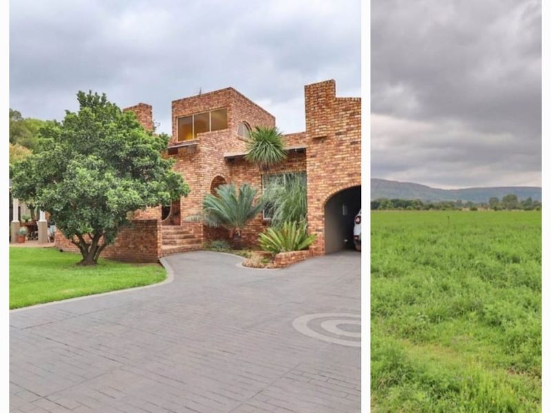 A front view of a face-brick small holding property featuring a paved driveway and expansive surrounding green fields.