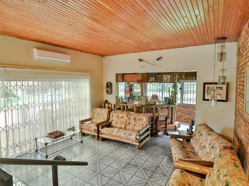 Spacious entertainment area featuring a built-in bar, exposed brick accents, timber ceiling, and direct access to the patio through sliding glass doors.