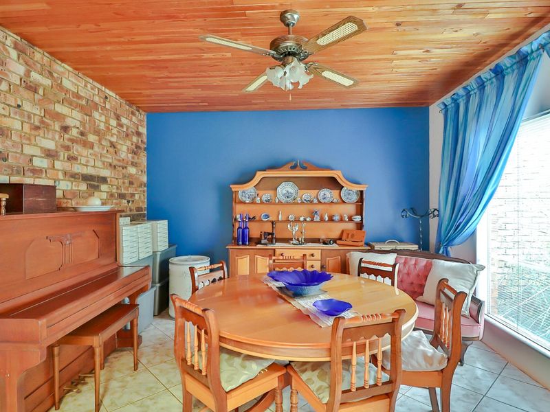Dining room featuring a timber ceiling, exposed brick feature wall, and tiled flooring, providing a warm and traditional atmosphere.