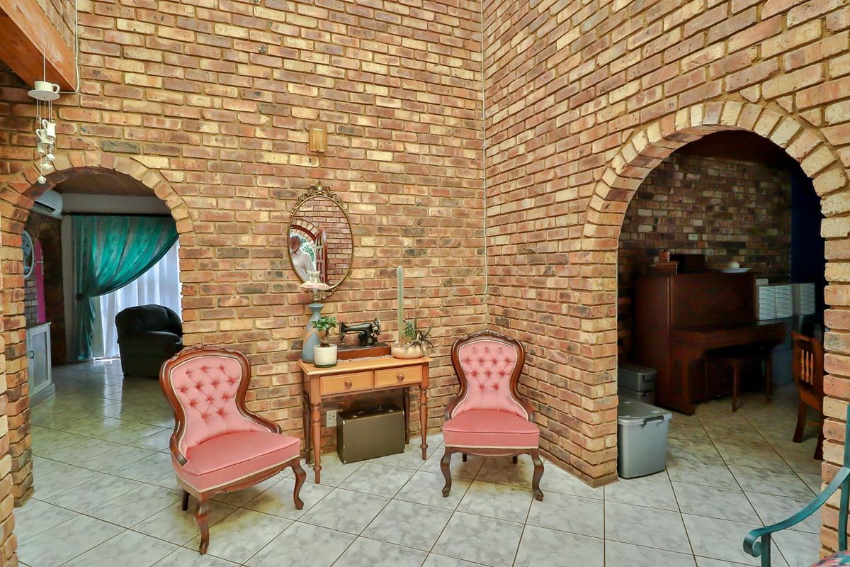 A living area featuring distinctive exposed brick walls, arched architectural openings, and tiled flooring, offering a rustic and character-filled space.