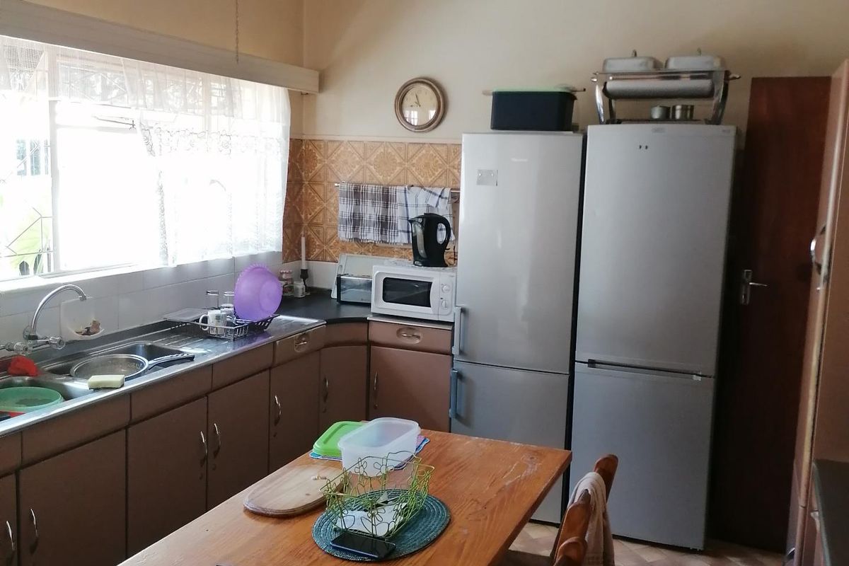 A dated kitchen featuring original cabinetry, tiled splashbacks, and vinyl flooring, offering a functional layout with potential for modern renovation.