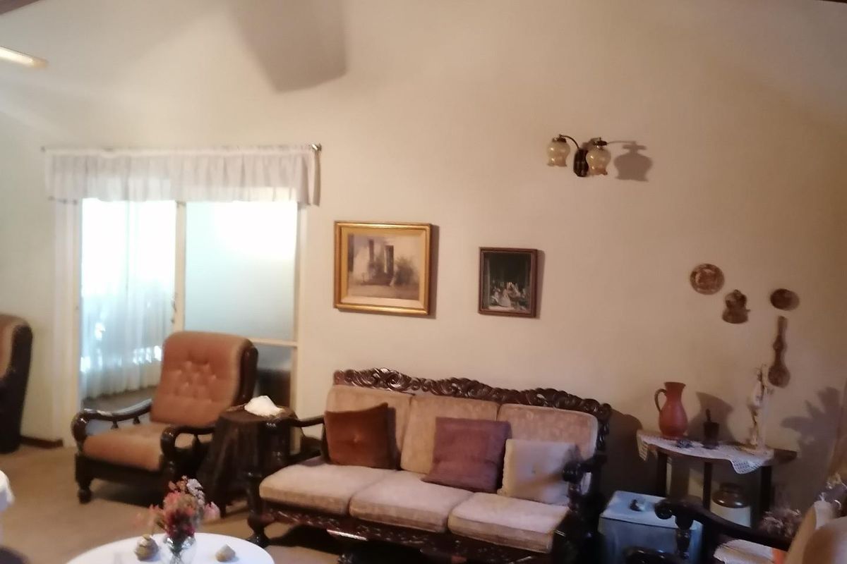 A spacious living room featuring a high vaulted wood-paneled ceiling and sliding glass door access to an outdoor area.
