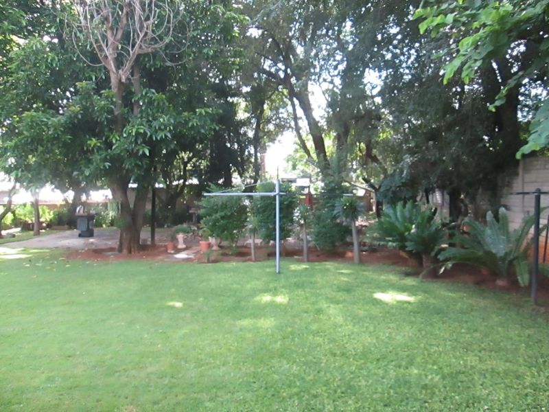 A spacious, well-maintained garden featuring a lush green lawn, mature trees, and established landscaping, providing a private and tranquil outdoor setting.