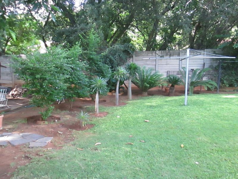 A private rear garden featuring a lawn, established trees, and a precast concrete boundary wall.