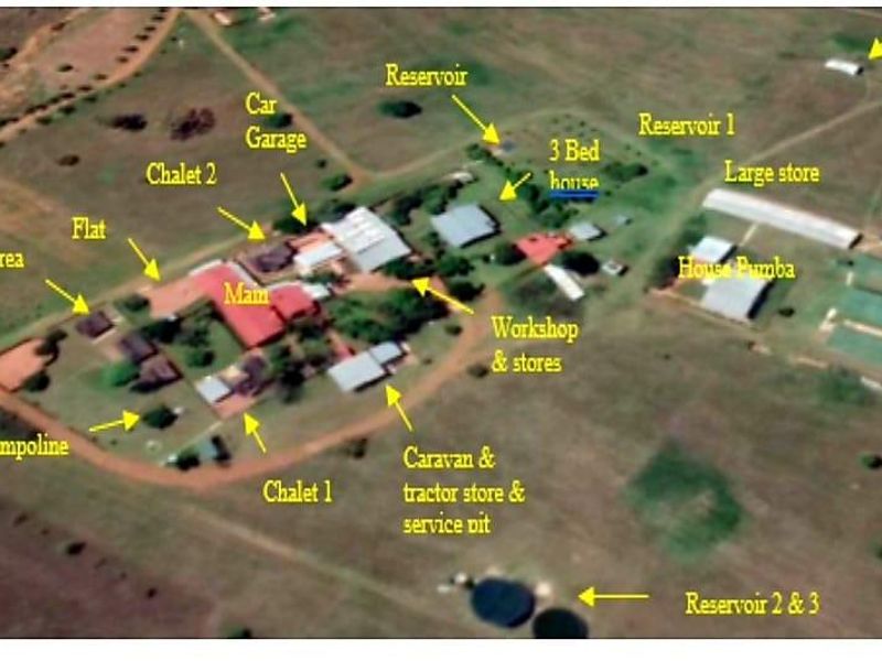 Aerial view of a farm property featuring multiple residential units, workshops, storage facilities, reservoirs, and a boma area.