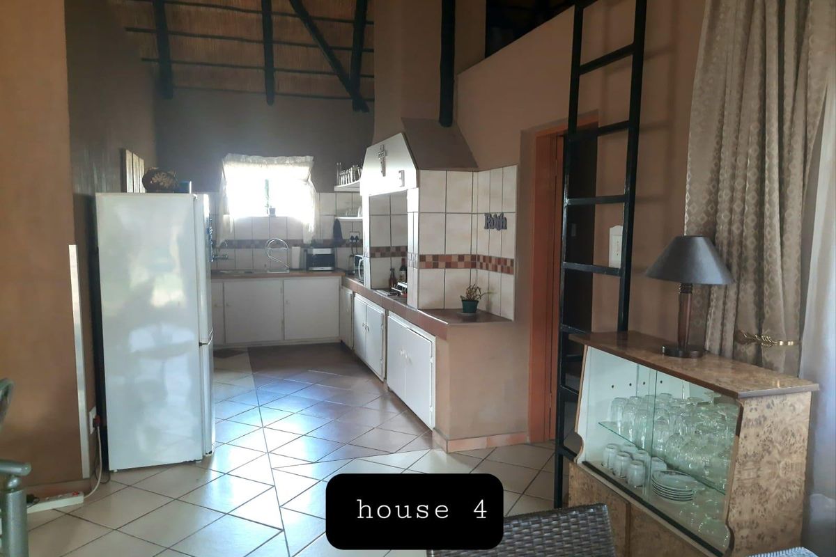 A rustic kitchen featuring tiled flooring, built-in cabinetry, and a distinctive thatched roof ceiling with an integrated fireplace.