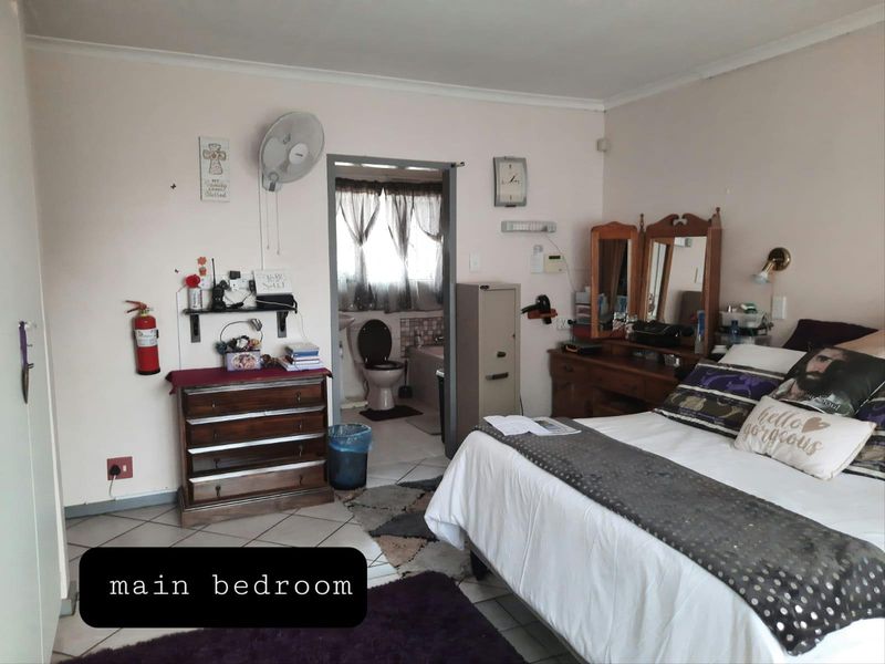 A functional main bedroom featuring tiled flooring, a wall-mounted fan, and direct access to an en-suite bathroom.