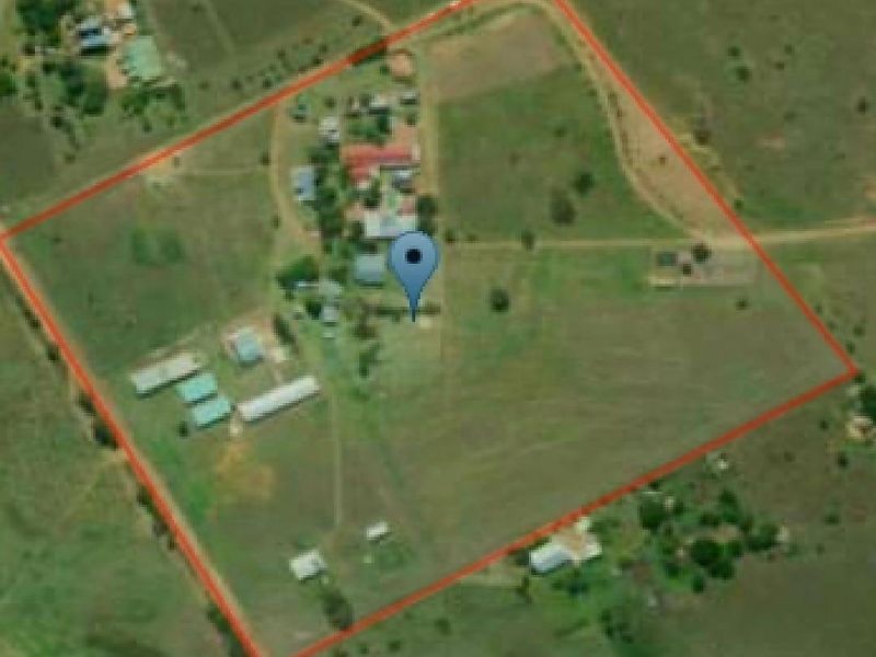 An aerial view of the farm property showing the main dwelling, various outbuildings, and the surrounding fenced land.