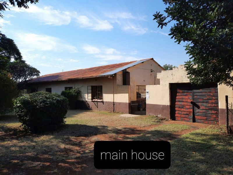 Front view of a farm house featuring a corrugated metal roof, brick exterior walls, and an attached garage structure.