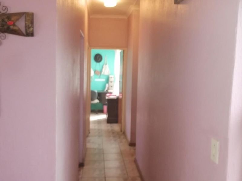 A simple residential hallway featuring tiled flooring and neutral wall finishes, providing access to adjacent rooms.