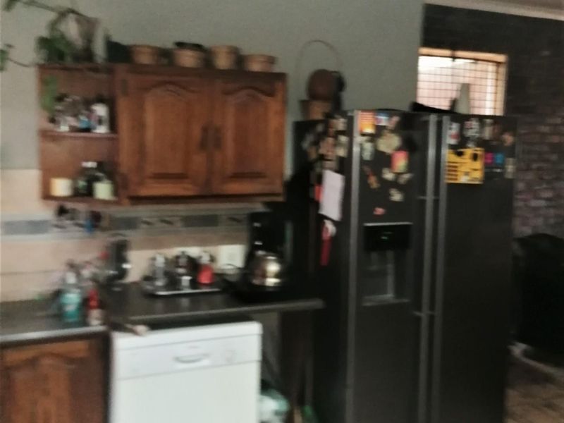 A functional kitchen area featuring wooden cabinetry, tiled flooring, and integrated appliance space, offering a practical layout for daily use.