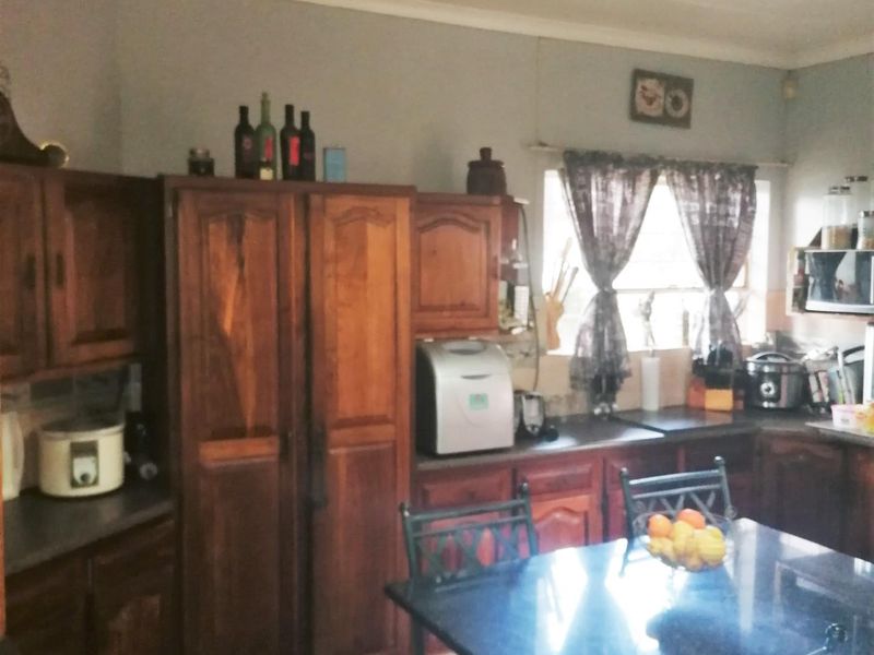A functional kitchen featuring traditional wooden cabinetry, tiled flooring, and ample counter space, offering a classic layout with potential for modern updates.