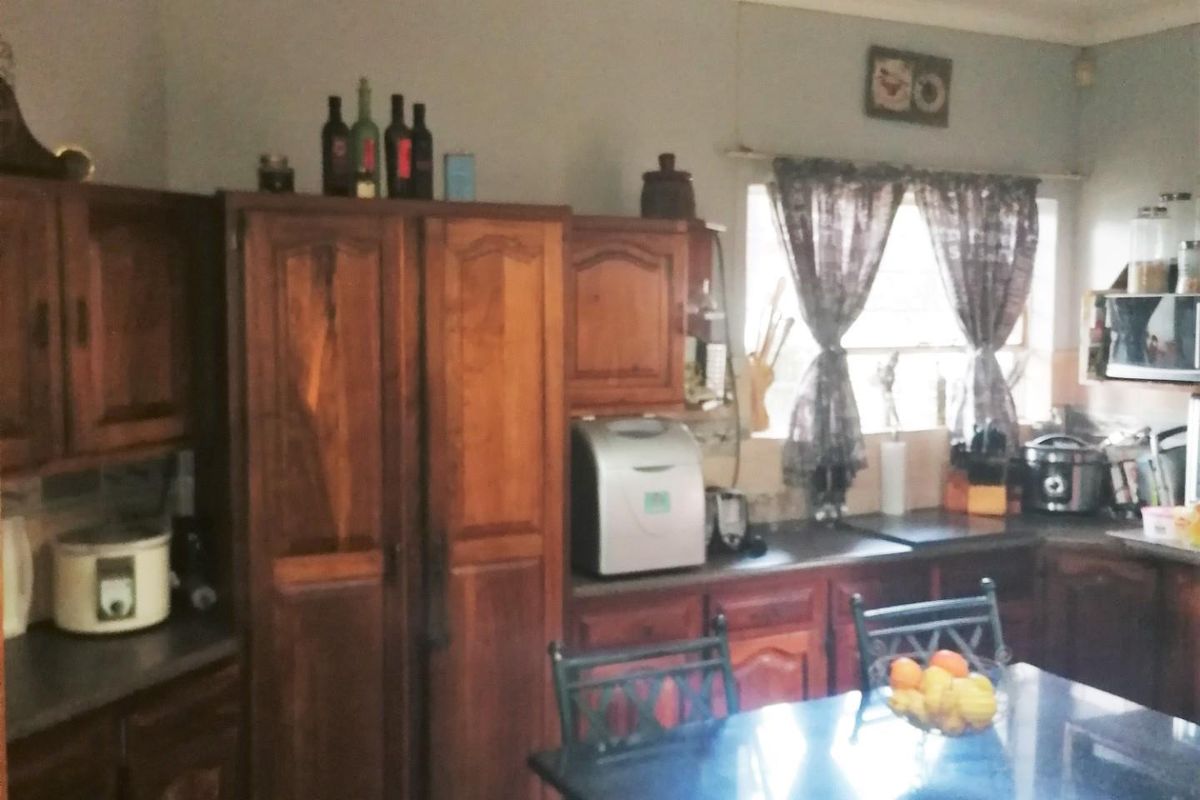 A functional kitchen featuring traditional wooden cabinetry, tiled flooring, and ample counter space, offering a classic layout with potential for modern updates.