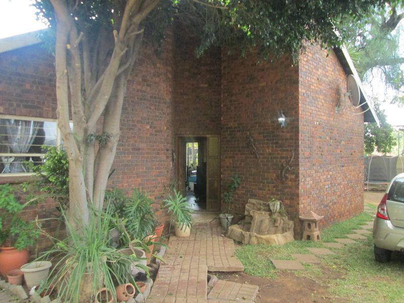 Front entrance of a face brick house featuring a paved walkway and a built-in garden water feature.