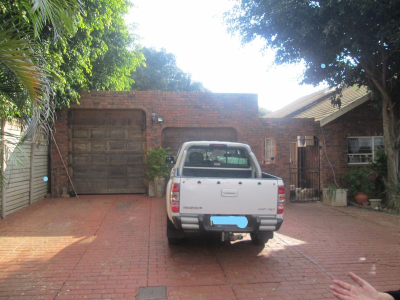 Front exterior view of the property featuring a brick facade, double garage, and paved driveway area.