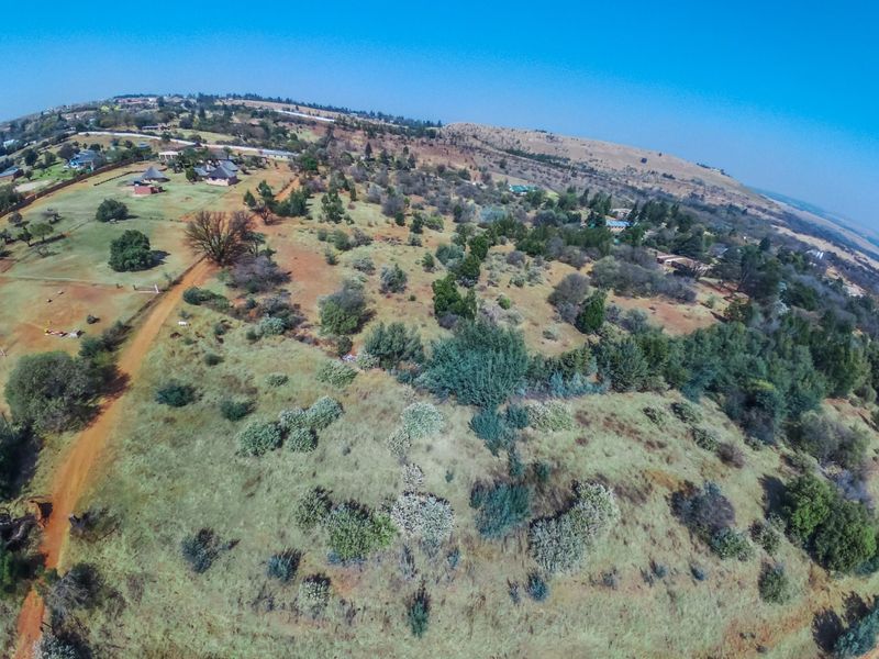 An aerial view of the expansive farm property, showcasing the natural landscape, vegetation, and existing structures across the terrain.