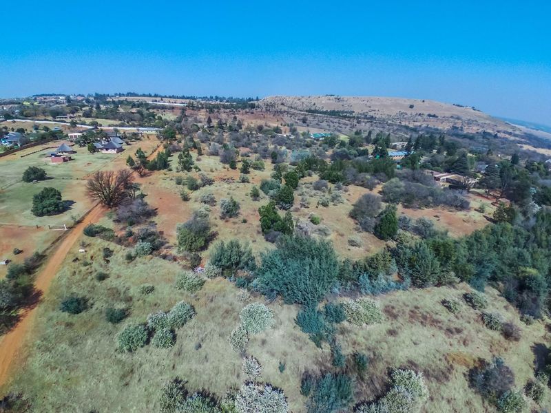 An aerial view of a large rural farm property featuring expansive natural vegetation, dirt access roads, and scattered outbuildings across the landscape.