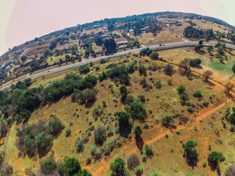 An aerial view of the farm property showing the surrounding landscape, natural vegetation, and adjacent road access.