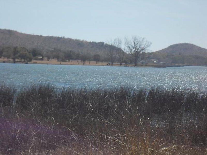 A scenic view of a lake with surrounding hills and natural vegetation, showcasing the tranquil landscape of the farm property.