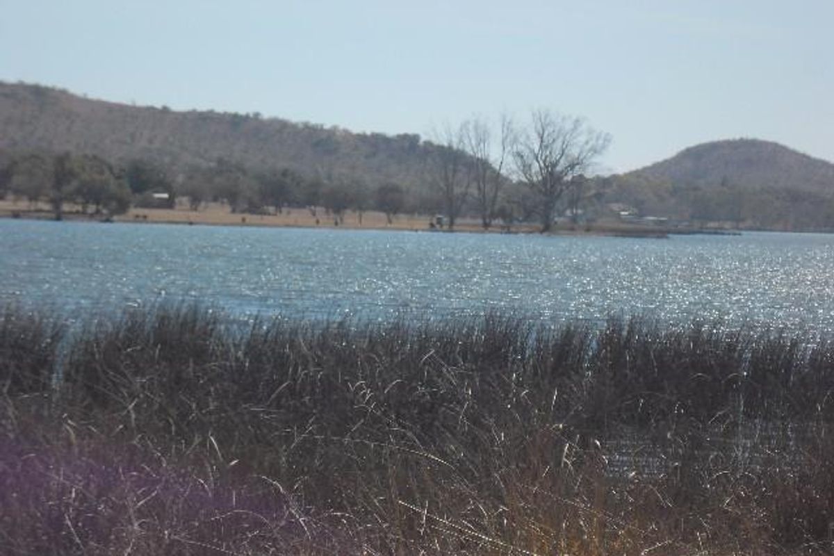 A scenic view of a lake with surrounding hills and natural vegetation, showcasing the tranquil landscape of the farm property.