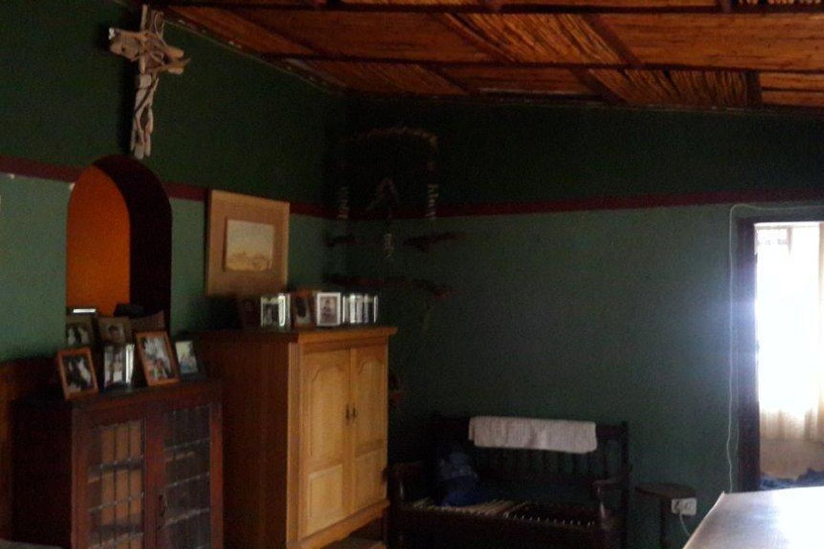 A living room featuring a traditional thatched ceiling, arched doorway, and wooden wainscoting, requiring cosmetic updates to improve the overall aesthetic.