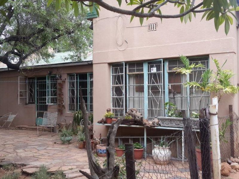 Rear exterior view of the small holding dwelling featuring a stone paved patio area, metal security window bars, and weathered exterior wall finishes.