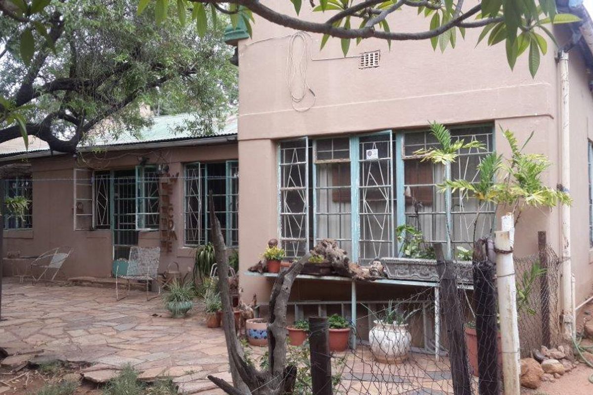 Rear exterior view of the small holding dwelling featuring a stone paved patio area, metal security window bars, and weathered exterior wall finishes.