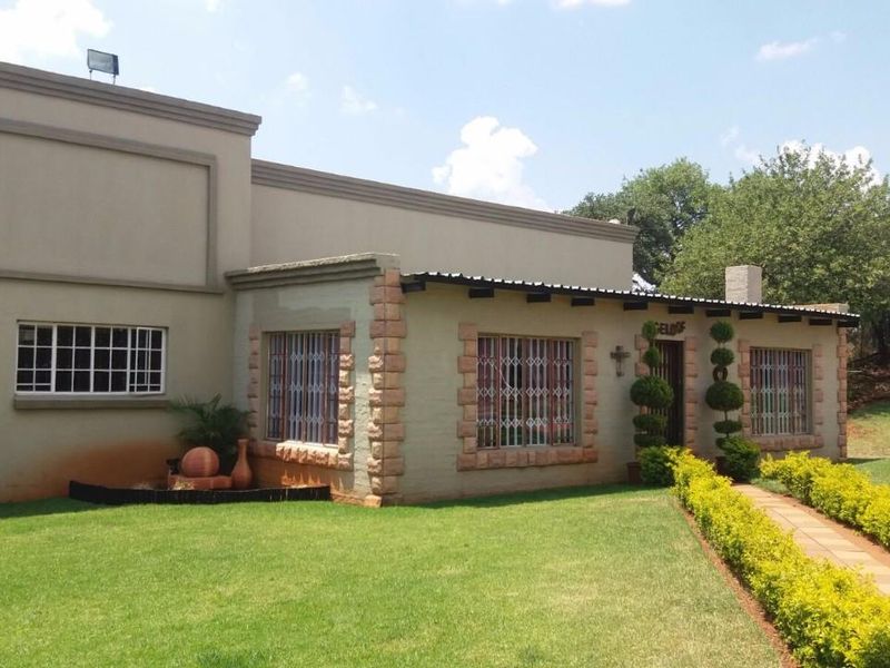 Front elevation of the property featuring stone-clad accents, security bars on windows, a paved walkway, and a well-maintained garden.