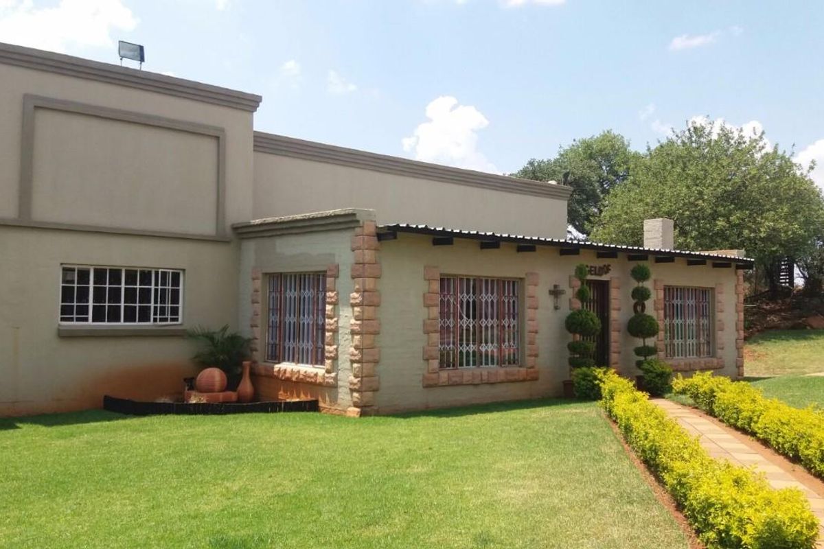 Front elevation of the property featuring stone-clad accents, security bars on windows, a paved walkway, and a well-maintained garden.
