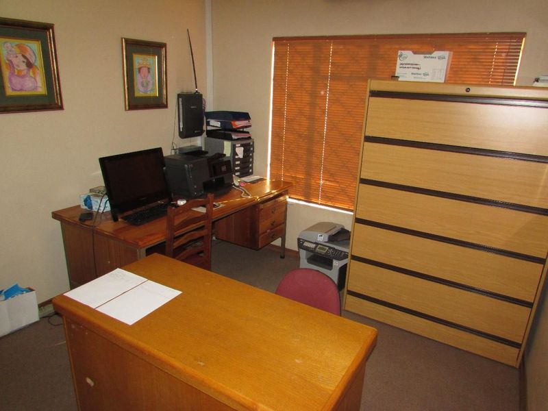 A functional office space featuring carpeted flooring and venetian blinds, providing a practical work environment.