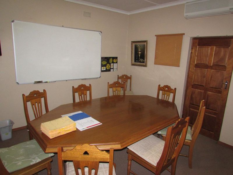 A functional office space featuring carpeted flooring, a wall-mounted whiteboard, and a split-system air conditioning unit.